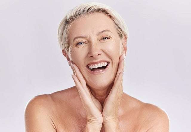 48222340 botox menopause and anti aging woman in beauty skincare or face wash portrait in a studio plastic surgery dermatology or cosmetics senior model with a smile touching her natural looking skin