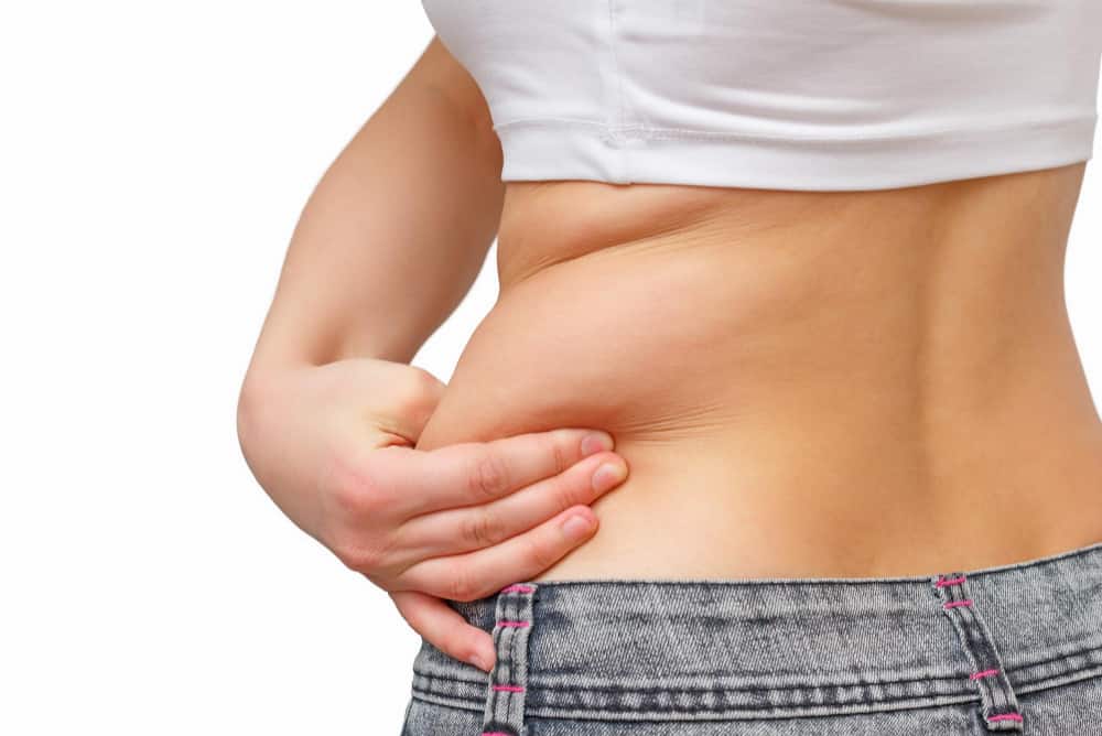 girl takes extra fat sides her stomach with her hand isolate white background